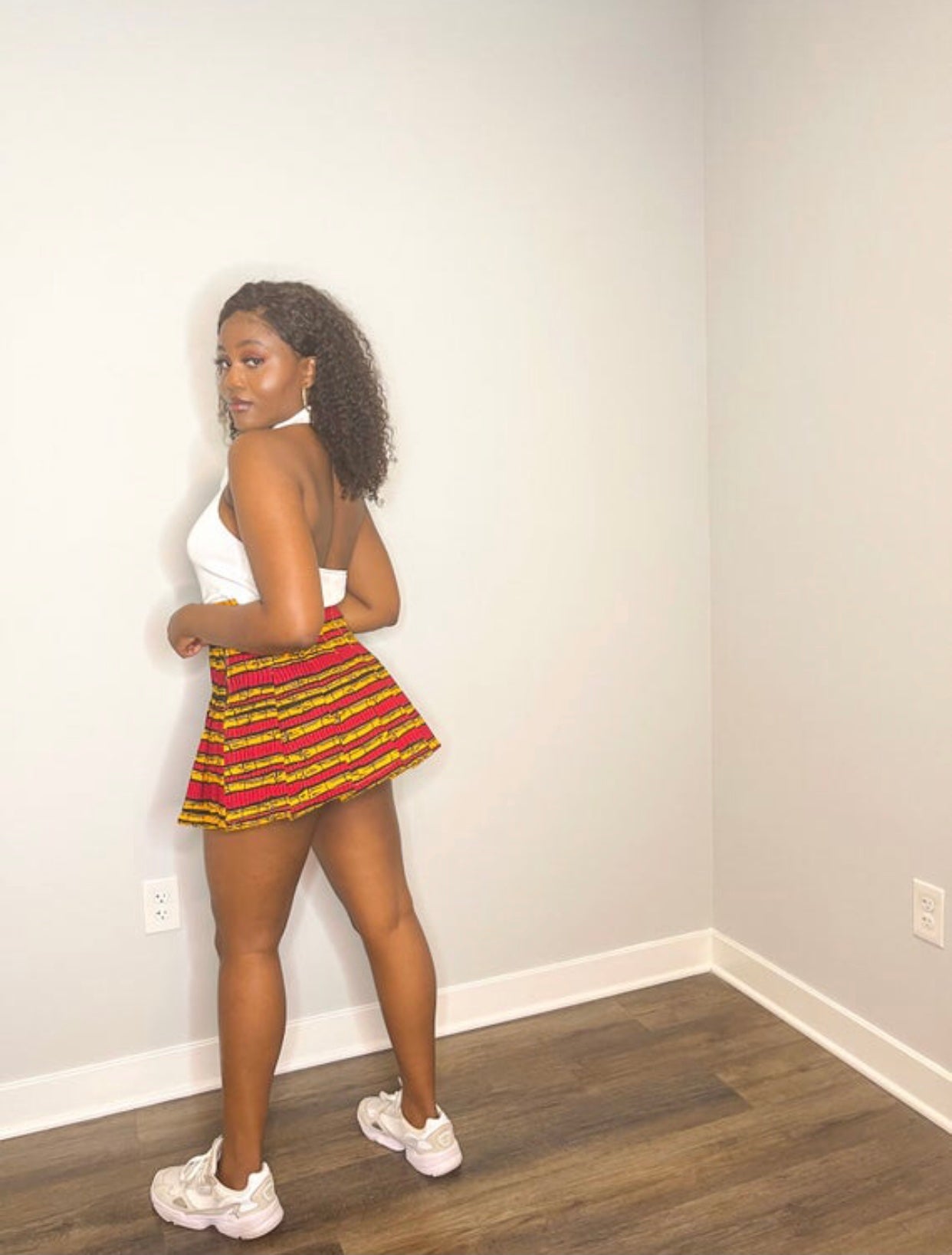 Sexy tennis/sporty pleated mini skirt made from a red, yellow and black sugarcane designed ankara fabric.