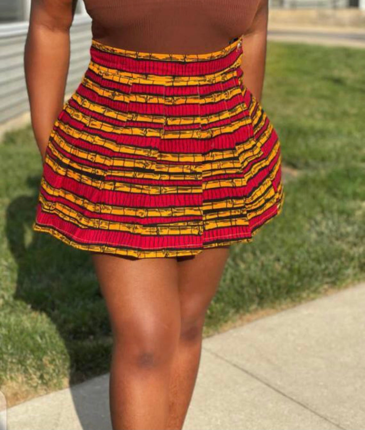 Sexy tennis/sporty pleated mini skirt made from a red, yellow and black sugarcane designed ankara fabric.