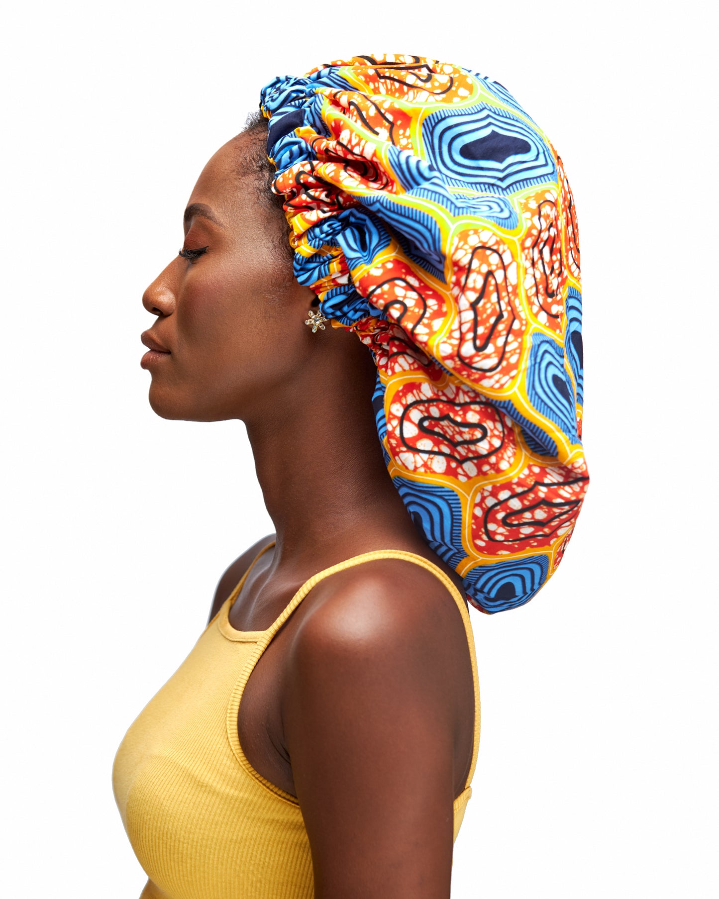 An Ankara Wax Print Made of Orange,White, Yellow, Seablue And Black Blend of Beautiful Colours And Pattern, Hand Made Elastic With Yellow Silk Lined Hair Bonnet